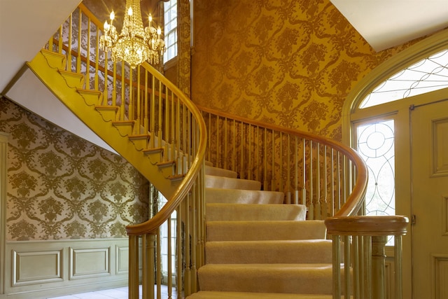 stairs with a notable chandelier and a towering ceiling