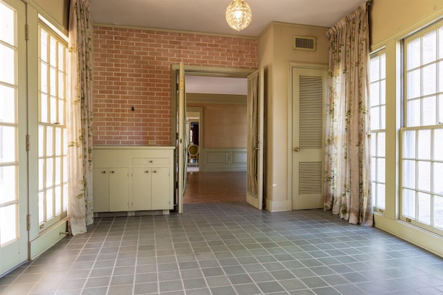 interior space with plenty of natural light, ornamental molding, and brick wall