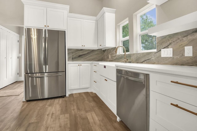 kitchen featuring hardwood / wood-style floors, decorative backsplash, white cabinetry, and appliances with stainless steel finishes