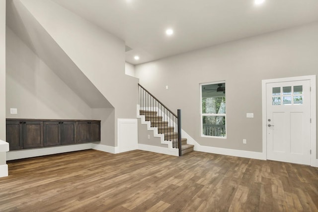 foyer with ceiling fan, a towering ceiling, and hardwood / wood-style flooring