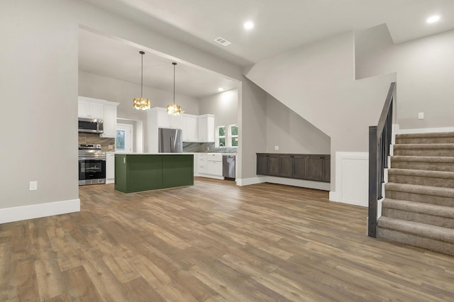 kitchen featuring white cabinetry, a center island, hanging light fixtures, light hardwood / wood-style flooring, and appliances with stainless steel finishes