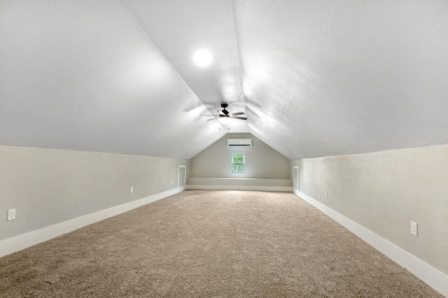 additional living space with carpet floors, vaulted ceiling, ceiling fan, and a wall unit AC