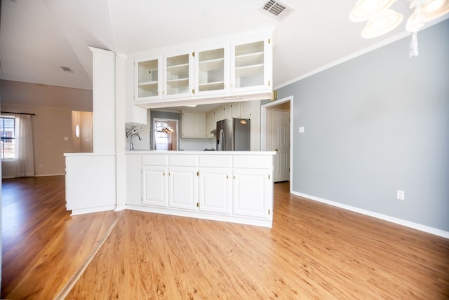 3712 Ashbury Ln, Nacogdoches, TX 75965 - kitchen featuring stainless steel fridge with ice dispenser, healthy amount of natural light, light wood finished floors, glass insert cabinets, and ornamental molding