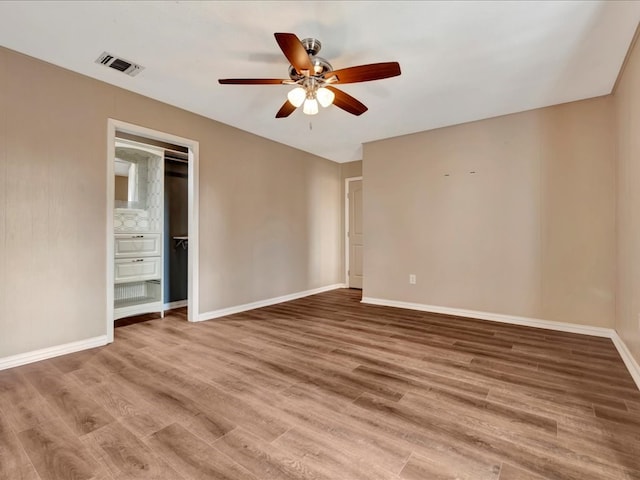 unfurnished room featuring baseboards, wood finished floors, visible vents, and ceiling fan