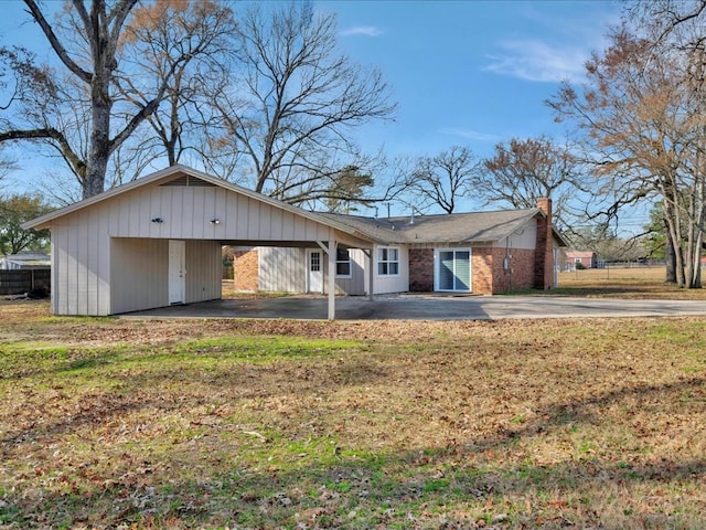 view of front of house featuring a front lawn, a carport, driveway, and a chimney