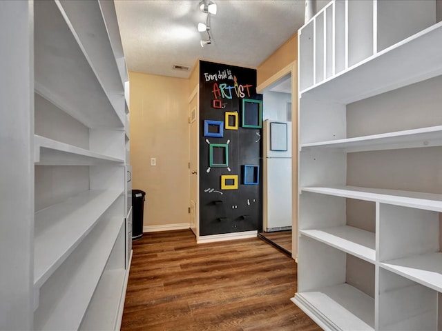 interior space with visible vents, baseboards, refrigerator, and wood finished floors