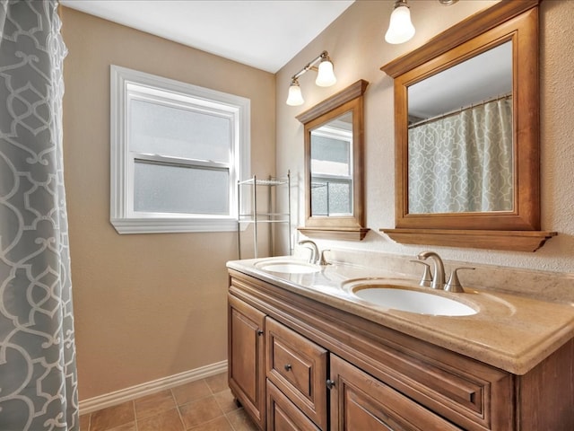 bathroom with a sink, baseboards, double vanity, and tile patterned floors