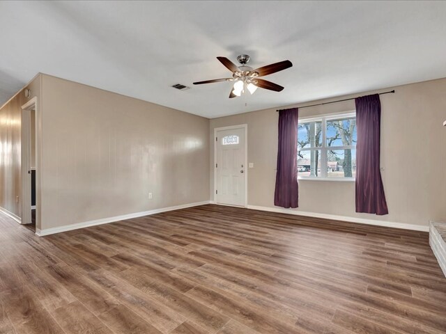 unfurnished living room with visible vents, baseboards, ceiling fan, and wood finished floors