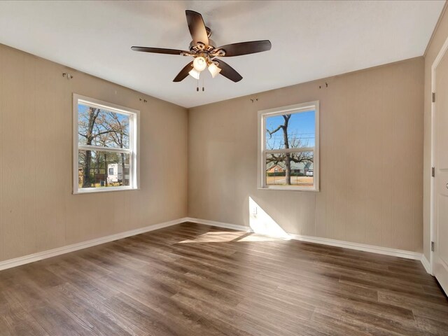 empty room with baseboards, plenty of natural light, wood finished floors, and a ceiling fan