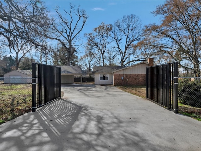 exterior space featuring an attached carport, driveway, fence, and a gate