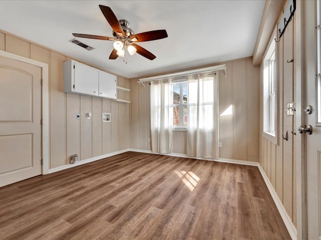 empty room featuring visible vents, wood finished floors, and a ceiling fan