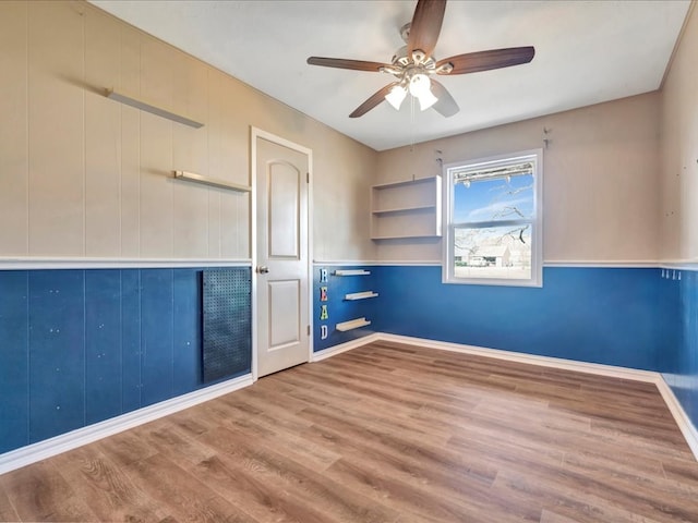 empty room with ceiling fan, baseboards, and wood finished floors