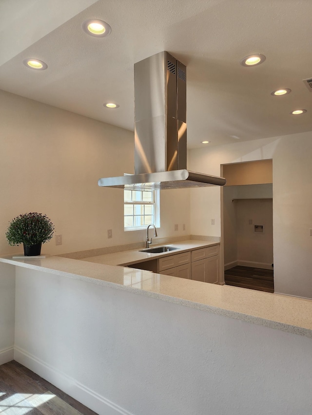 kitchen featuring kitchen peninsula, island range hood, sink, and dark wood-type flooring