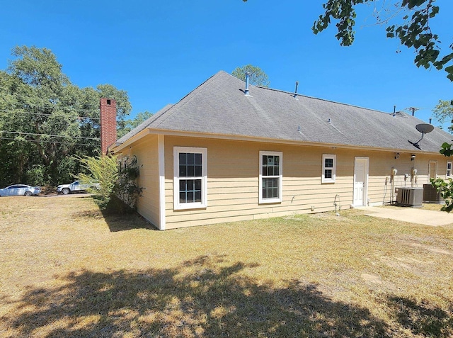 rear view of property featuring a lawn, a patio area, and central AC unit