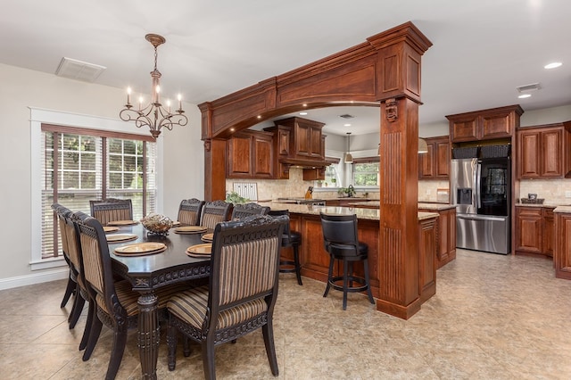 dining space featuring decorative columns, plenty of natural light, and a notable chandelier