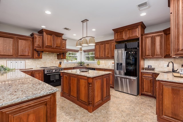 kitchen featuring stainless steel appliances, hanging light fixtures, a kitchen island, sink, and light stone counters