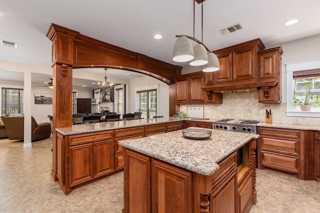 kitchen featuring pendant lighting, ceiling fan with notable chandelier, a wealth of natural light, and stainless steel gas stovetop