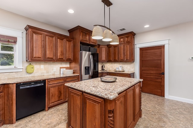 kitchen featuring light stone counters, dishwasher, a kitchen island, stainless steel fridge, and hanging light fixtures