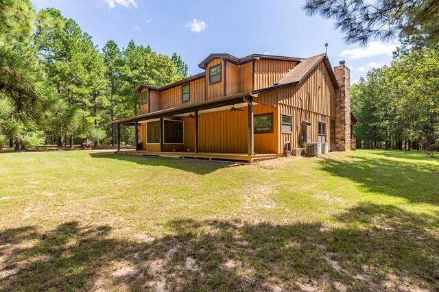 rear view of house with central AC and a lawn