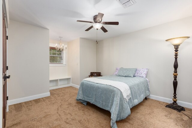 carpeted bedroom with ceiling fan with notable chandelier