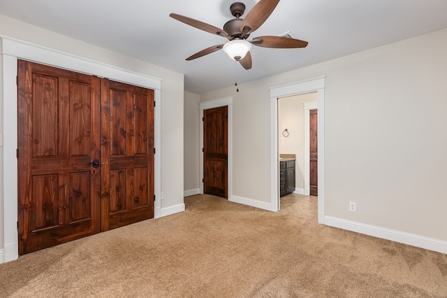 unfurnished bedroom with ceiling fan, ensuite bathroom, light carpet, and a closet