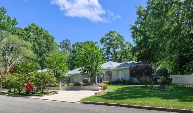 view of front of home with a front yard, fence, and concrete driveway