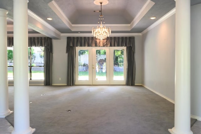 interior space with ornamental molding, a raised ceiling, and decorative columns