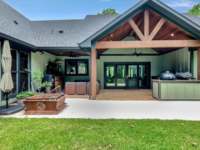 back of property with a ceiling fan, a patio area, and roof with shingles