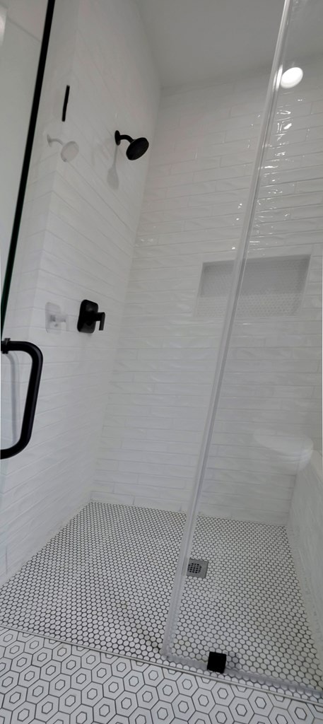 full bathroom with tile patterned flooring and a shower stall