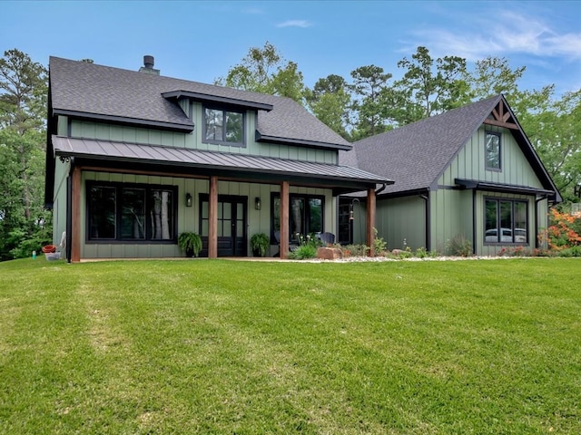 view of front of house with board and batten siding, a standing seam roof, a shingled roof, and a front yard