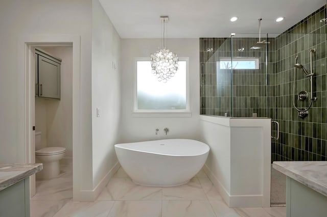 full bathroom featuring vanity, marble finish floor, a freestanding tub, baseboards, and a stall shower