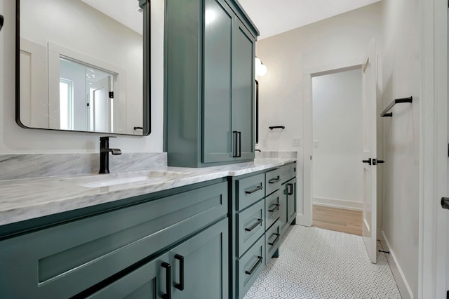 bathroom with double vanity, baseboards, a sink, and tile patterned floors