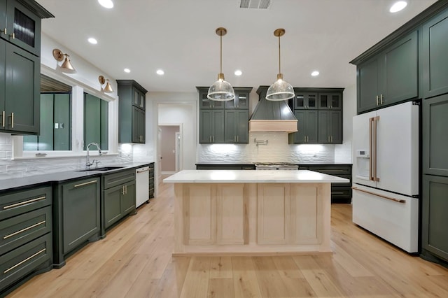 kitchen with white appliances, green cabinetry, custom exhaust hood, and a sink