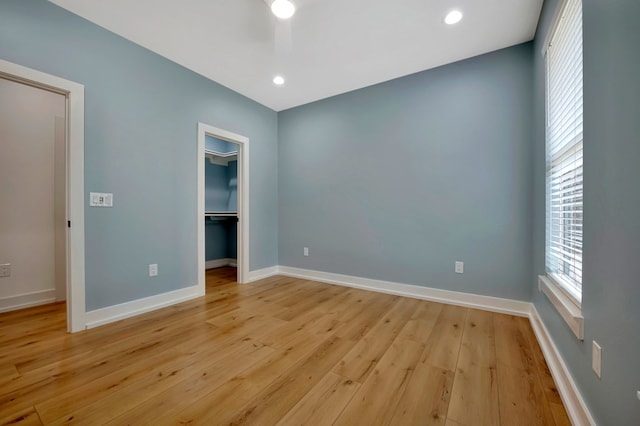 unfurnished bedroom with baseboards, a closet, light wood finished floors, a spacious closet, and recessed lighting