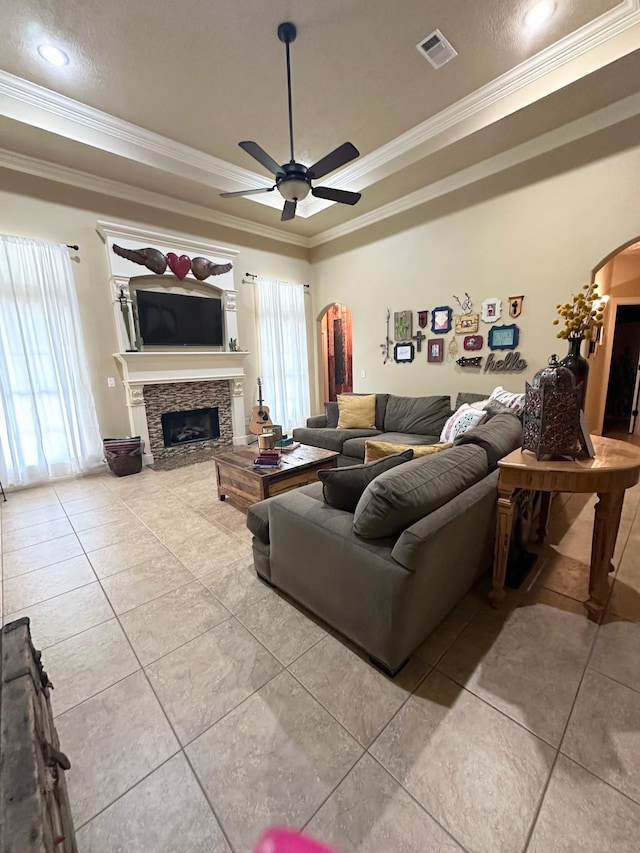 living room with light tile patterned floors, a tray ceiling, ceiling fan, and ornamental molding