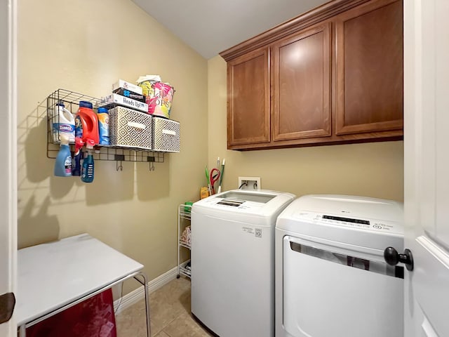 washroom featuring light tile patterned flooring, cabinets, and washing machine and clothes dryer