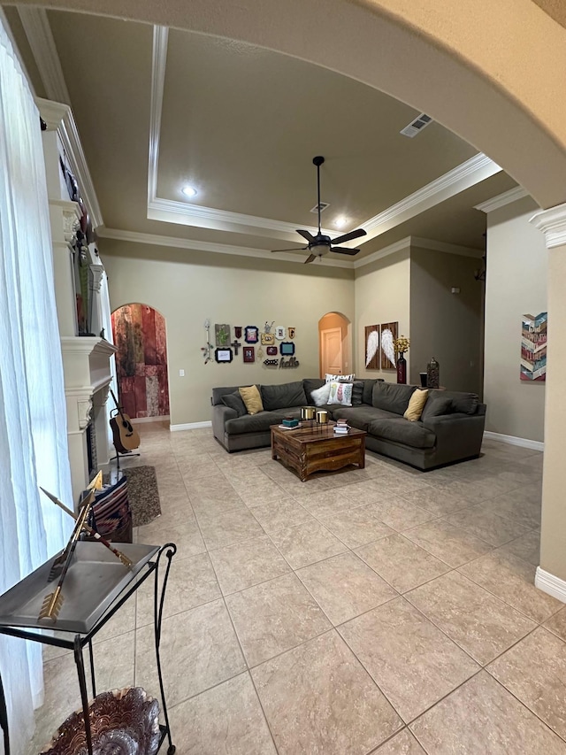 living room with a tray ceiling, ceiling fan, crown molding, and light tile patterned floors