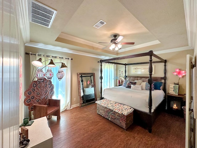 bedroom with hardwood / wood-style floors, ceiling fan, ornamental molding, and a tray ceiling