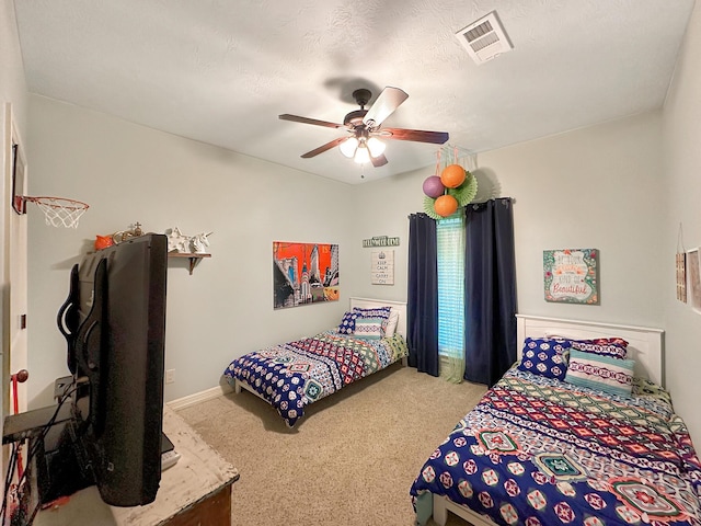 carpeted bedroom featuring ceiling fan and a textured ceiling