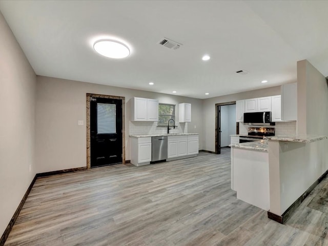 kitchen with kitchen peninsula, white cabinetry, sink, and appliances with stainless steel finishes