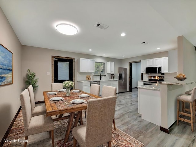 dining room featuring sink and light hardwood / wood-style floors