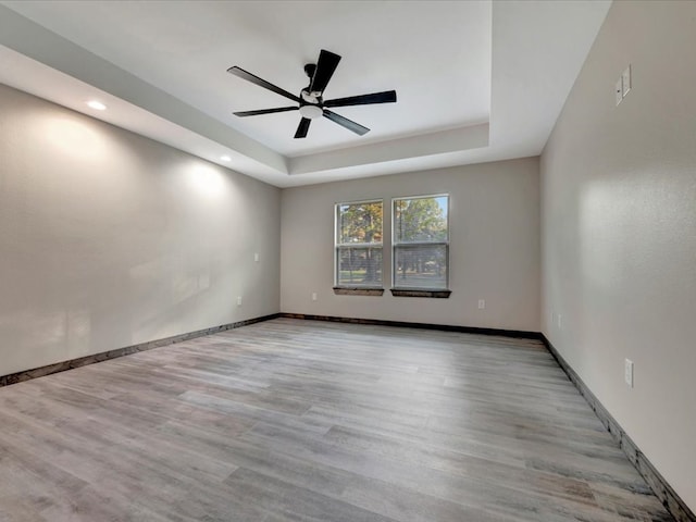 spare room featuring ceiling fan, a raised ceiling, and light hardwood / wood-style flooring