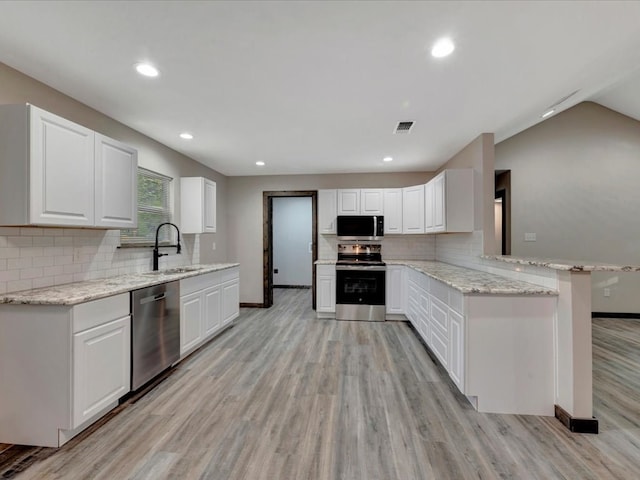 kitchen with white cabinets, sink, light hardwood / wood-style flooring, appliances with stainless steel finishes, and kitchen peninsula