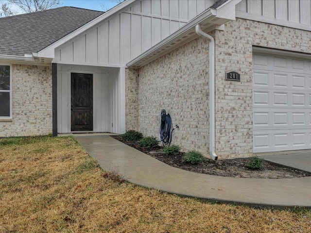 doorway to property with a garage and a lawn