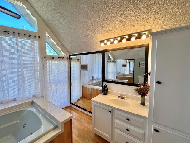 bedroom featuring hardwood / wood-style flooring, ceiling fan, a textured ceiling, and lofted ceiling