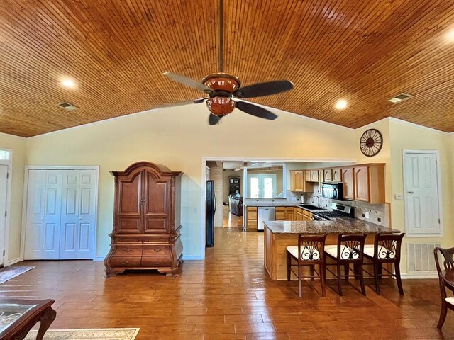 kitchen featuring lofted ceiling, a breakfast bar, dark hardwood / wood-style floors, black appliances, and kitchen peninsula