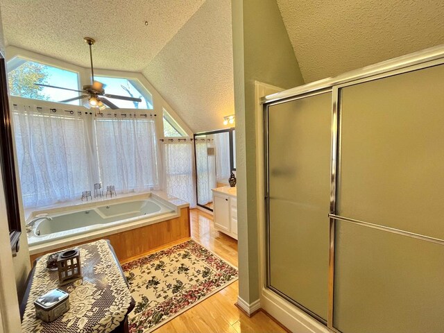 bathroom with hardwood / wood-style floors, lofted ceiling, a textured ceiling, toilet, and tiled bath