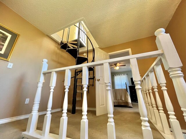 stairway with carpet floors, a textured ceiling, and ceiling fan