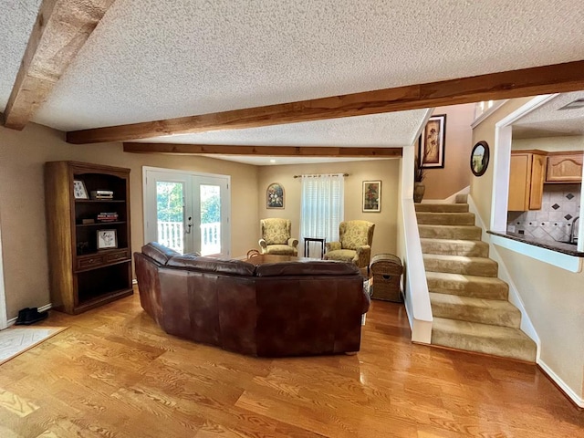 living room featuring a textured ceiling, french doors, beamed ceiling, and light hardwood / wood-style flooring