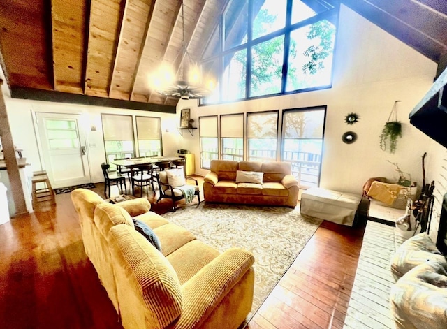 living room featuring beamed ceiling, wood-type flooring, plenty of natural light, and ceiling fan